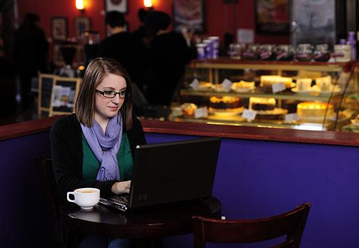 学生在咖啡馆拿着笔记本电脑.